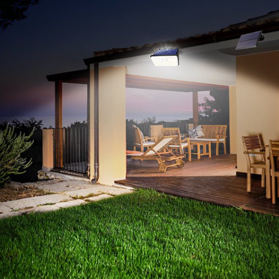 Projecteur exterieur solaire illuminant une pelouse derriere une maison 